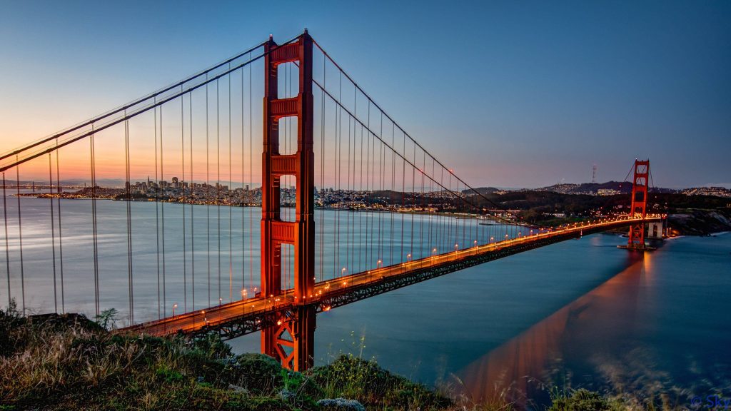 Golden Gate Bridge glowing at twilight with San Francisco skyline and orange sunset sky wallpaper
