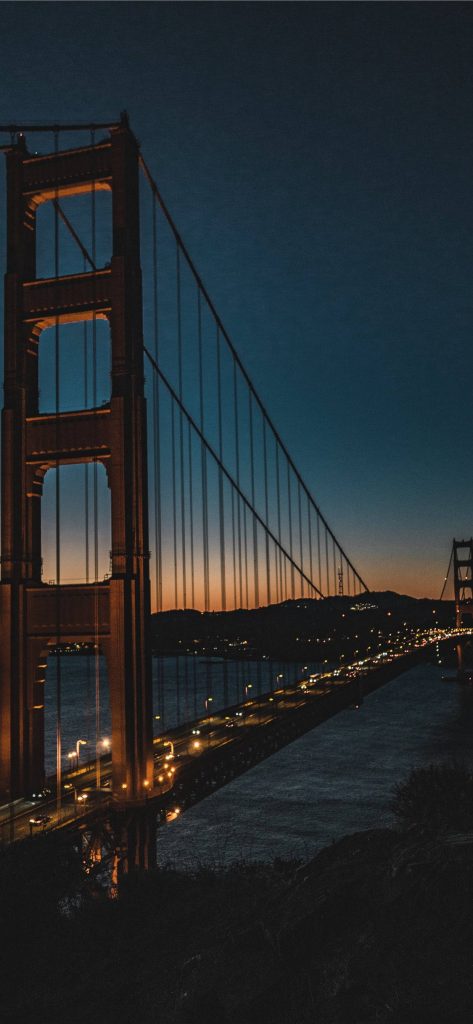 Golden Gate Bridge twilight iPhone wallpaper with warm lights and blue sunset over water