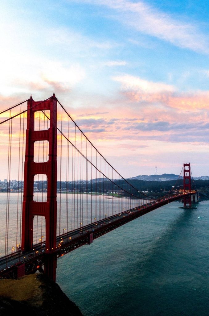 High-angle view of Golden Gate Bridge at sunset with pastel sky and calm water wallpaper background