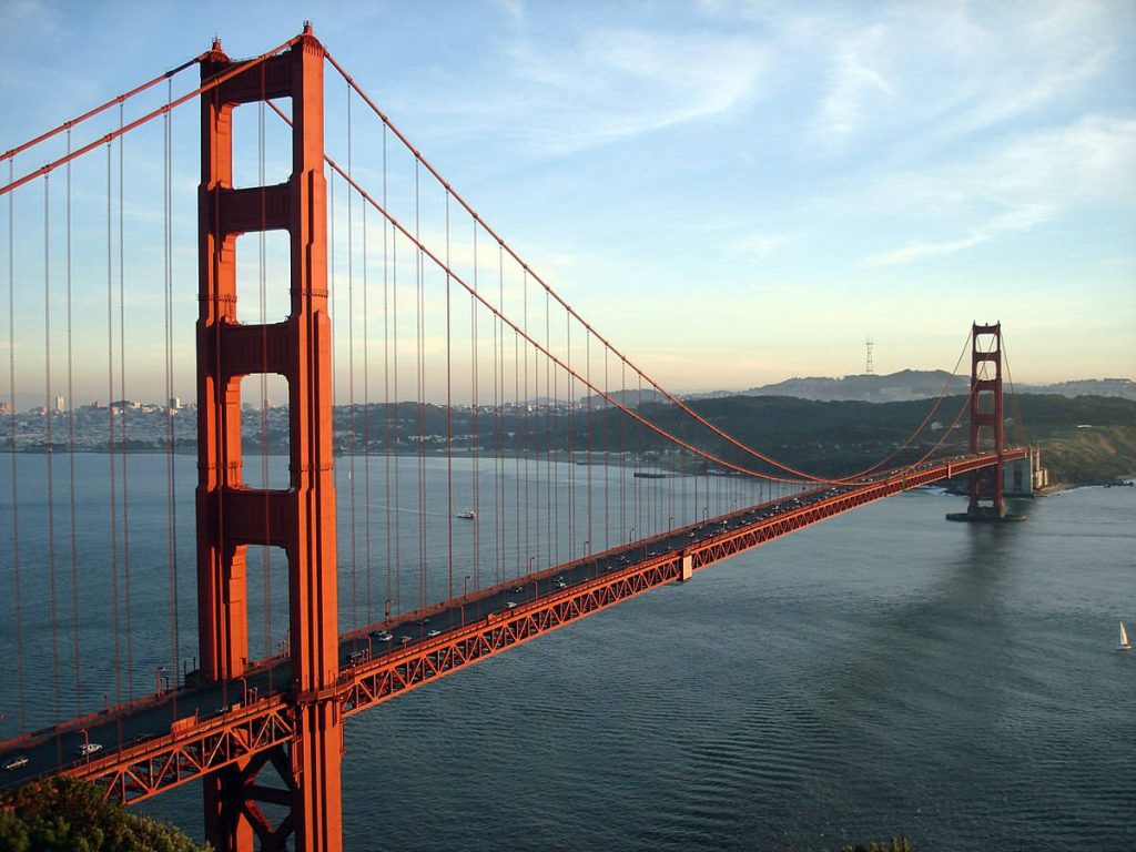 Golden Gate Bridge in warm golden light spanning serene San Francisco Bay at sunset Wallpaper