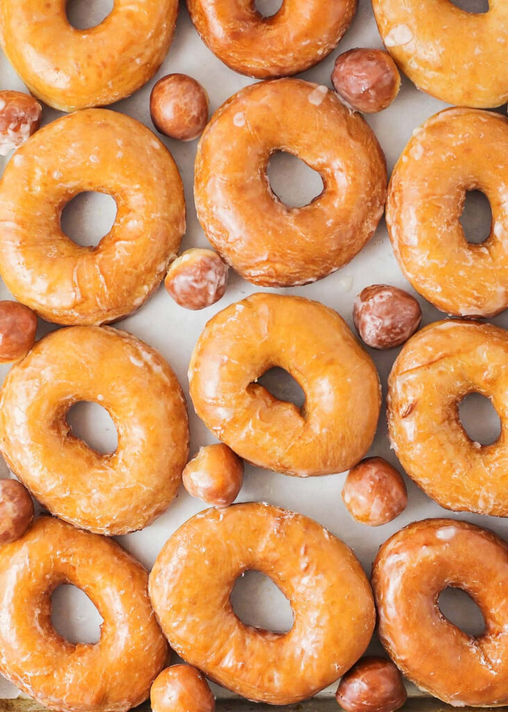 Golden glazed donuts and holes in a repetitive grid wallpaper with shiny soft texture background