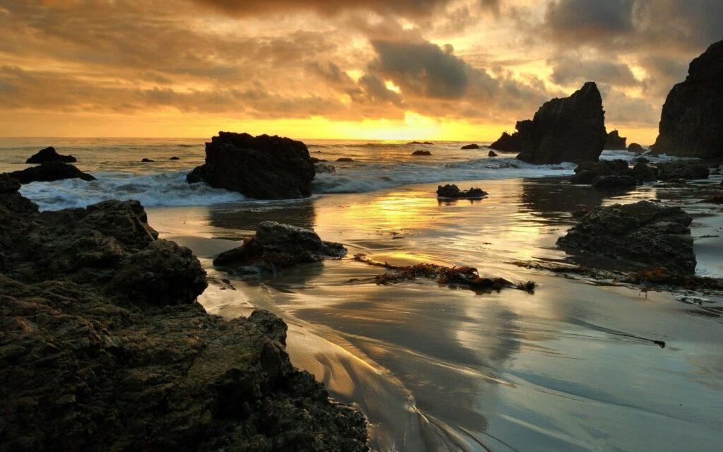 Golden Horizon: Mesmerizing Malibu Sunrise amidst Majestic Rock Formations for Desktop screens Wallpaper