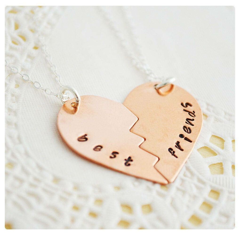 Golden Heart Friendship Keepsake: Intimate Close-up of Best Friends' Matching Necklace Wallpaper