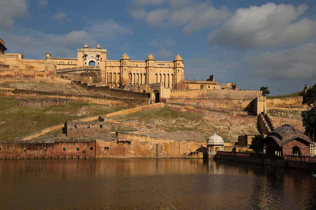 Golden hour at Amer Fort with warm sunlight reflecting on majestic architecture and calm water Wallpaper