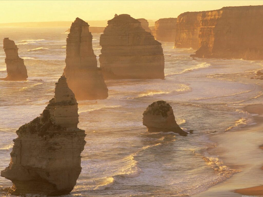Australian coastline with golden light sea stacks rugged rocks and soft mist wallpaper background