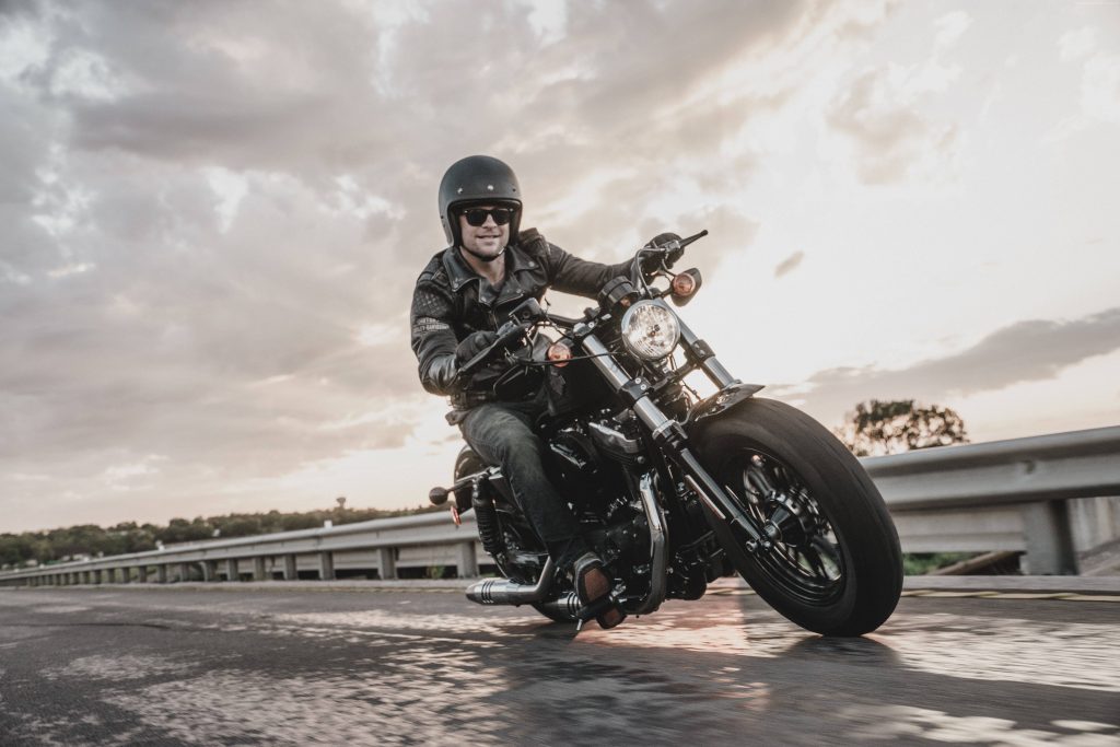Black Harley-Davidson motorcycle with biker cruising highway at golden hour sunset wallpaper