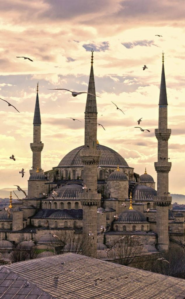 Blue Mosque Istanbul at sunset with glowing domes and minarets against a serene sky Wallpaper