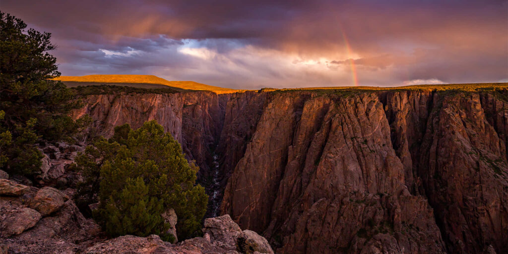Black Canyon golden light with dramatic cliffs lush greenery vibrant sky serene nature view wallpaper
