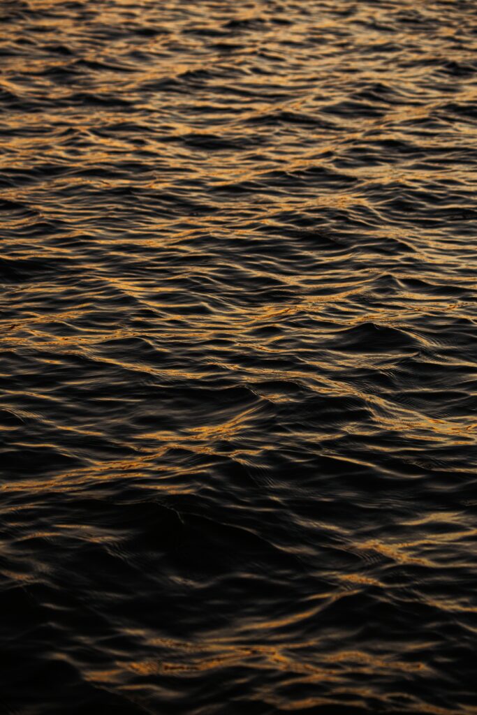 Golden light reflecting on gentle water waves creating calming natural texture wallpaper background