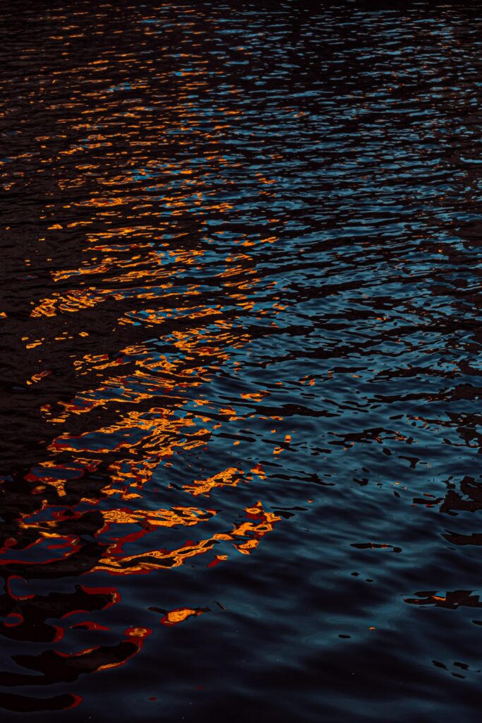 Water ripples illuminated by golden light with deep blue and vibrant orange reflections wallpaper