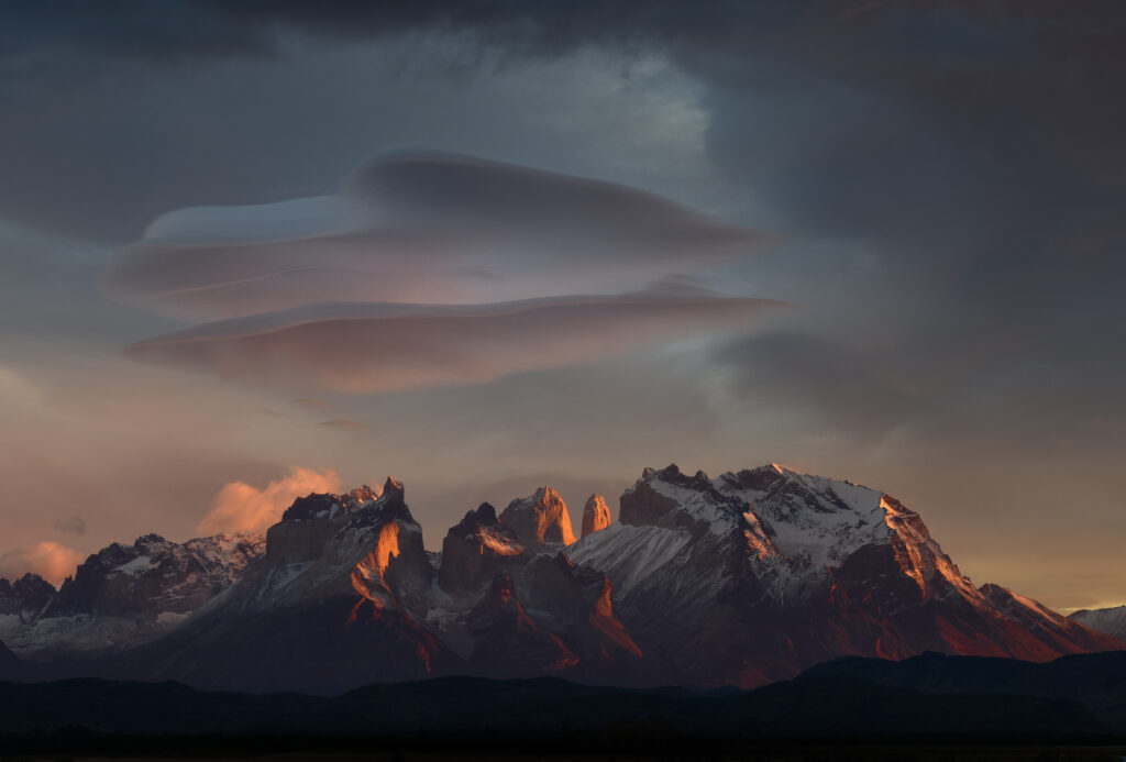 Rugged mountain peaks with snow under golden light and dramatic dark clouds landscape wallpaper