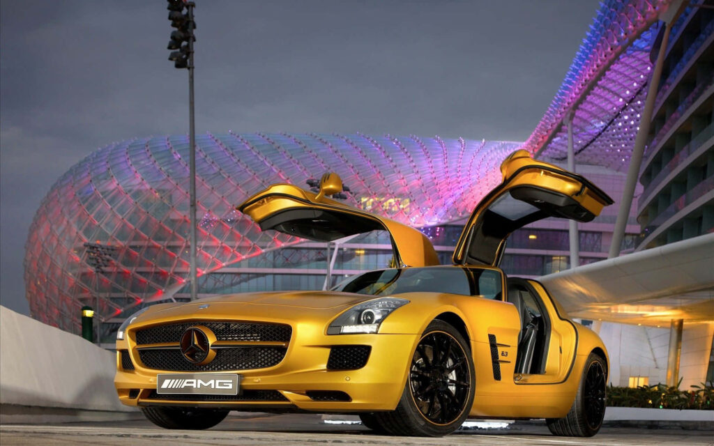 Gold Mercedes-Benz AMG with open gullwing doors under vibrant architectural lights wallpaper
