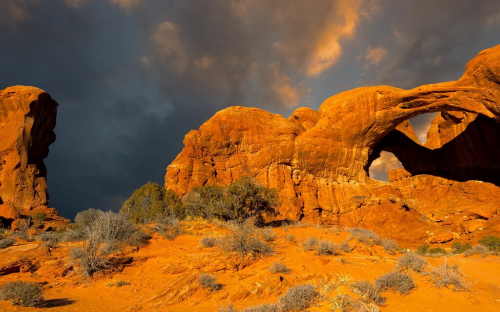 Rugged mountains with golden orange hues under a dynamic sky scenic wallpaper background
