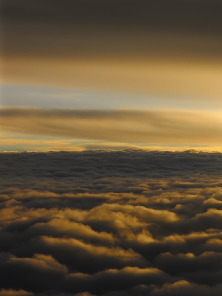Golden yellow porous clouds stretching across horizon in dramatic serene sky wallpaper background