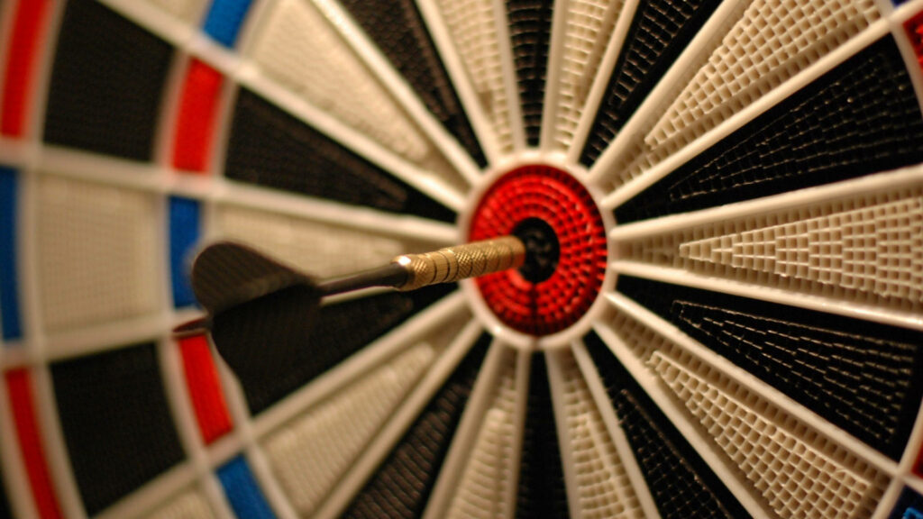 Bullseye Focus: Close-Up of Golden Dart on Blurred Target Board Wallpaper