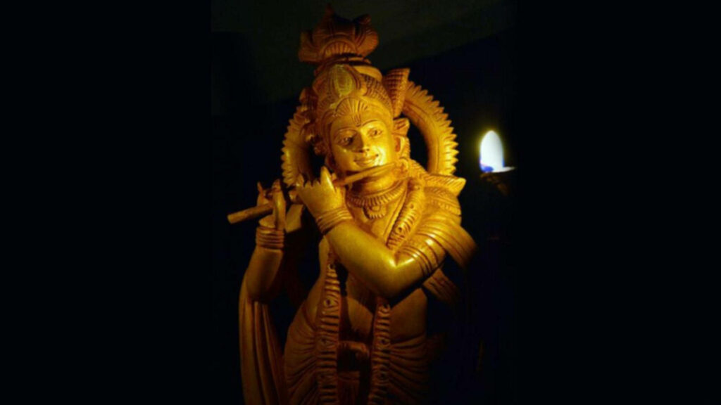 A Captivating Glimpse: Illuminated Dark Krishna Statue Enhancing the Enigmatic Background Wallpaper