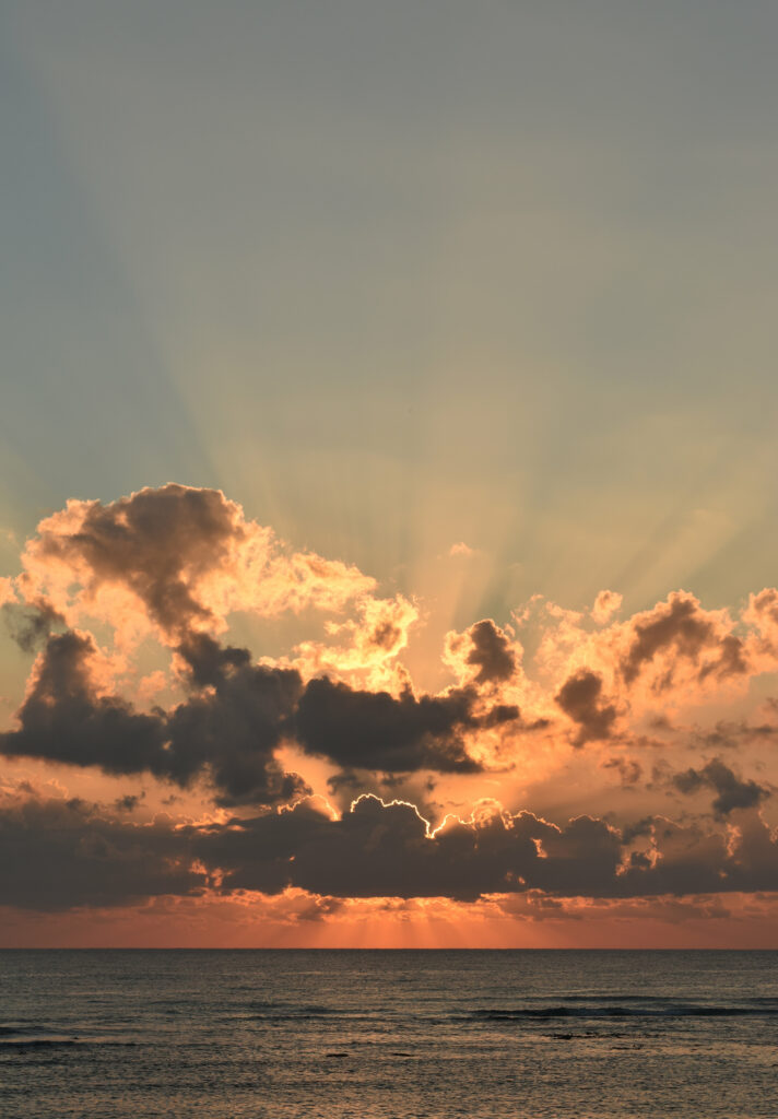 Sunset golden rays through clouds over calm sea horizon vibrant orange and blue sky wallpaper