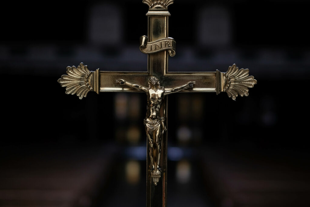 Resplendent Savior: A Gilded Jesus Statue Resplendent on the Cross, Amidst a Majestic Chapel Backdrop Wallpaper