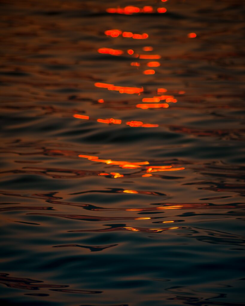 Close-up of water ripples reflecting warm golden light creating a tranquil shimmering wallpaper