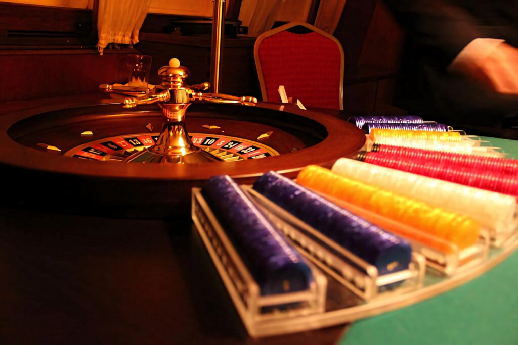 Golden roulette wheel with colorful chips on warm luxurious casino wallpaper background