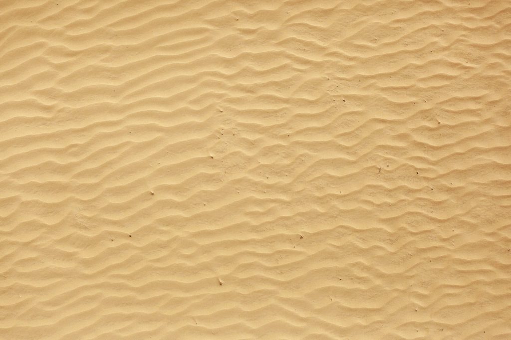 Close-up of golden sand dunes with intricate ripple patterns in warm tan tones wallpaper background