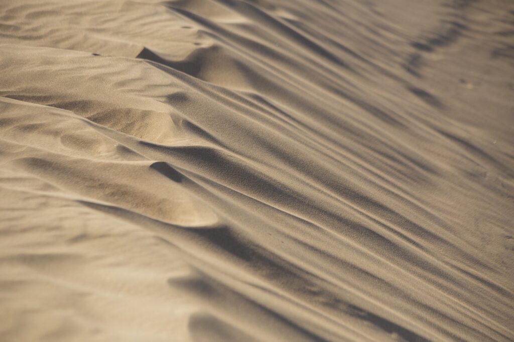 Soft golden sand dunes with textured curves and shadows minimalist natural wallpaper background