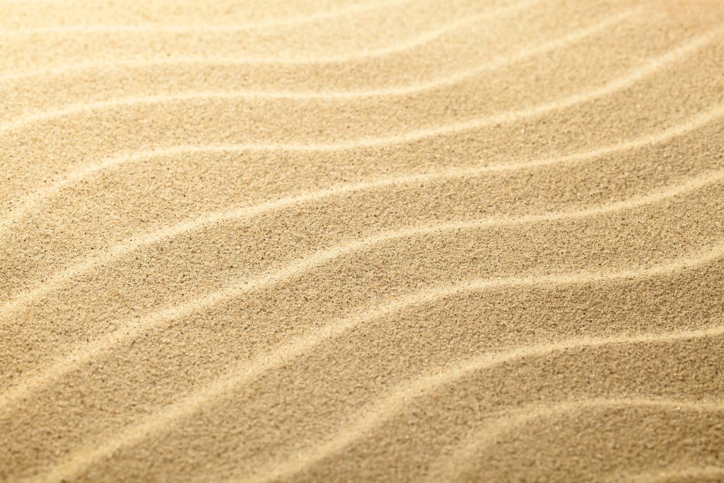Close-up of golden sand ripples with soft natural light showing detailed desert textures wallpaper