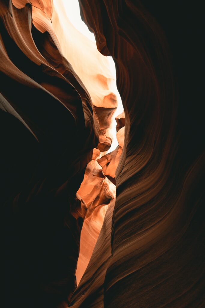 Bottom view of narrow sandstone canyon with golden light highlighting textured rocky walls Wallpaper