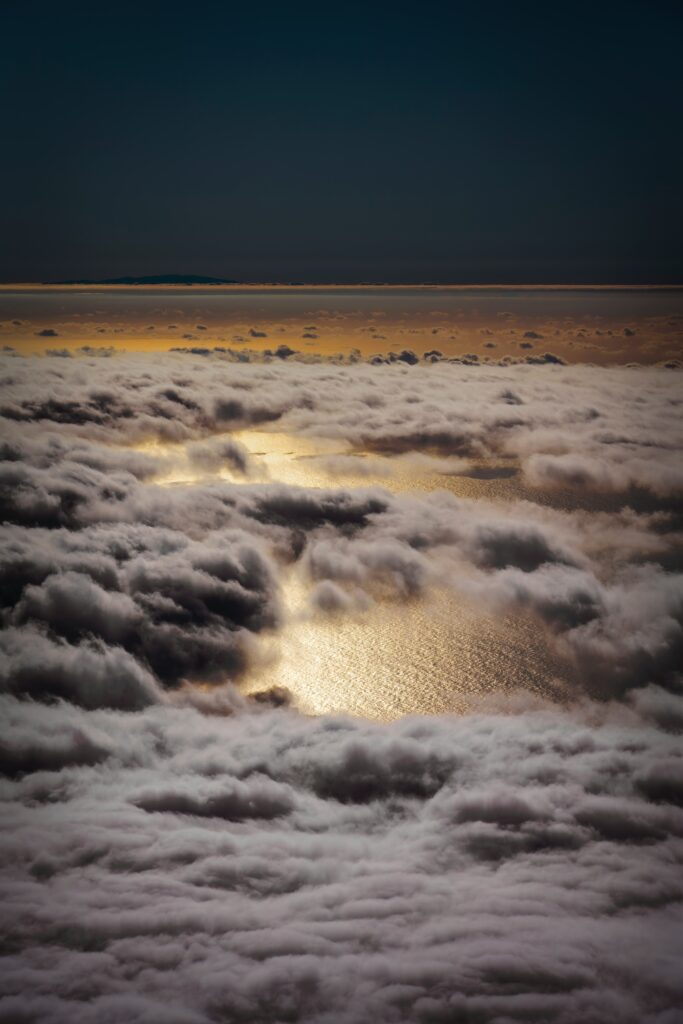 Aerial view above clouds showing golden shimmering sea and warm sunlight dreamy wallpaper background
