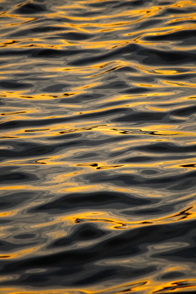 Golden shimmering waves on rippling water creating a tranquil nature-inspired abstract wallpaper background