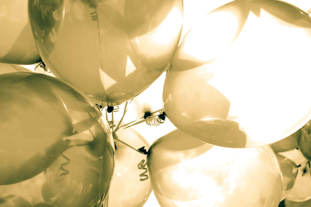 Shiny golden balloons cluster glowing in warm light festive celebration wallpaper background