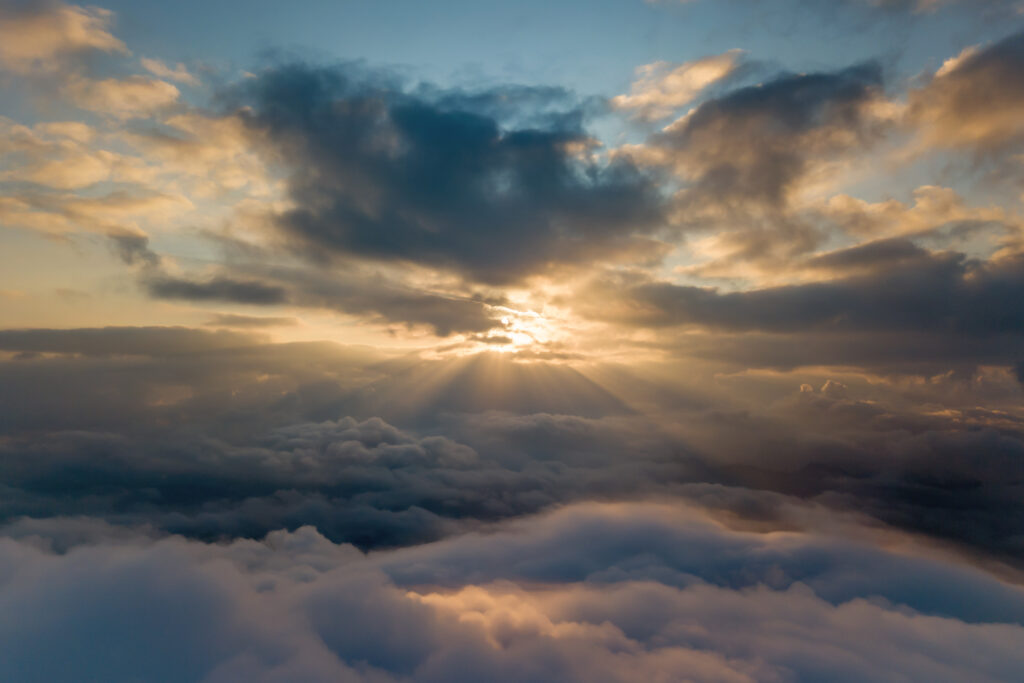 Dramatic sky with golden sun rays breaking through clouds creating serene nature wallpaper