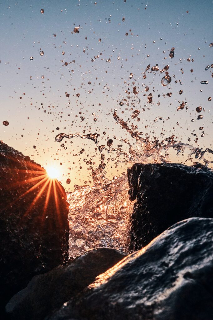 Golden sunlight between wet stones with water spray and shimmering droplets in motion wallpaper