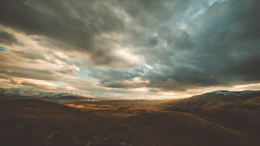 Golden sunlight through clouds over rolling Armenian mountains and vast serene landscape wallpaper