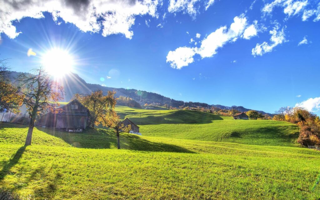 Golden sunlight over green lawns and rustic lodge in serene autumn landscape with clear blue sky Wallpaper
