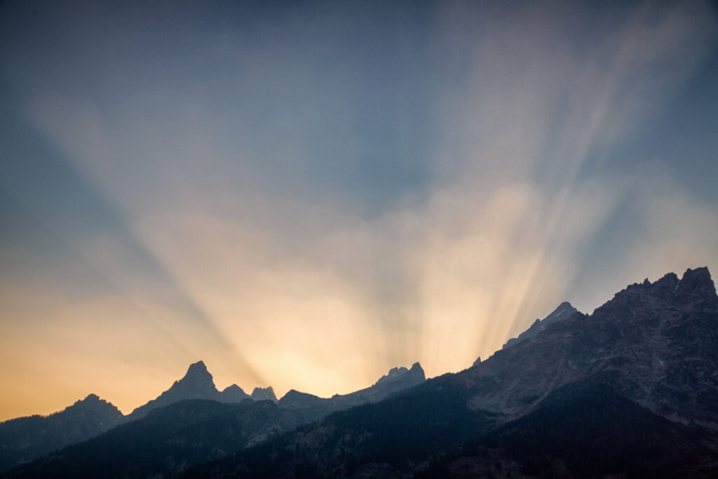 Golden sunlight over jagged mountain peaks at sunset with warm and cool gradient sky background Wallpaper