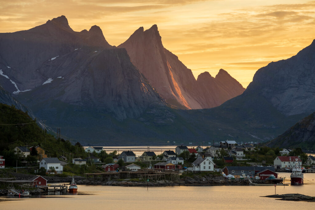 Golden sunlight over serene Nordic island village between mountains and calm sea waters wallpaper