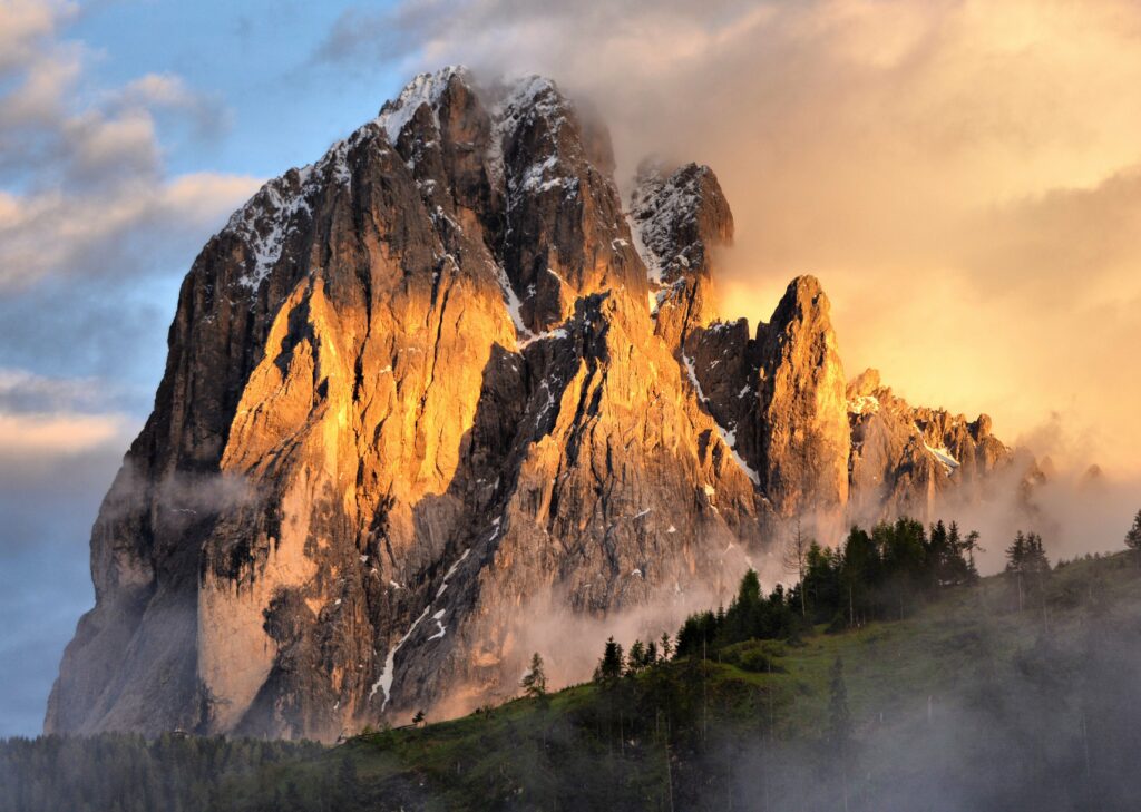 Golden sunlight on rugged mountain rocks with misty fog and drifting clouds landscape wallpaper