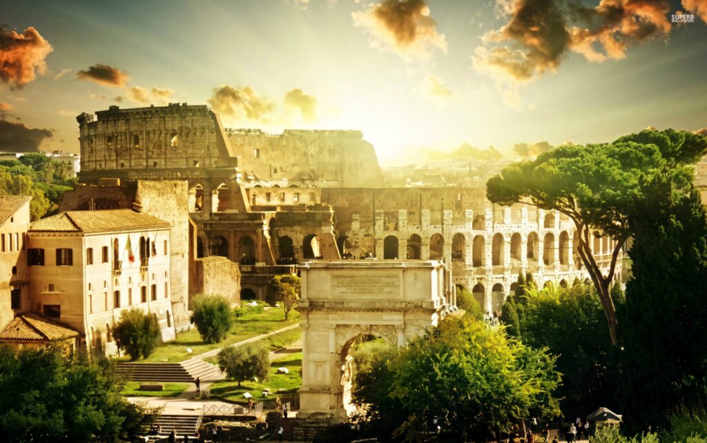 Colosseum glowing in golden sunlight with lush green trees under a dramatic sunlit sky wallpaper