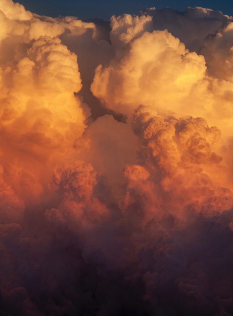 Dramatic thick clouds lit by golden sunlight with rich colors creating a warm textured sky Wallpaper