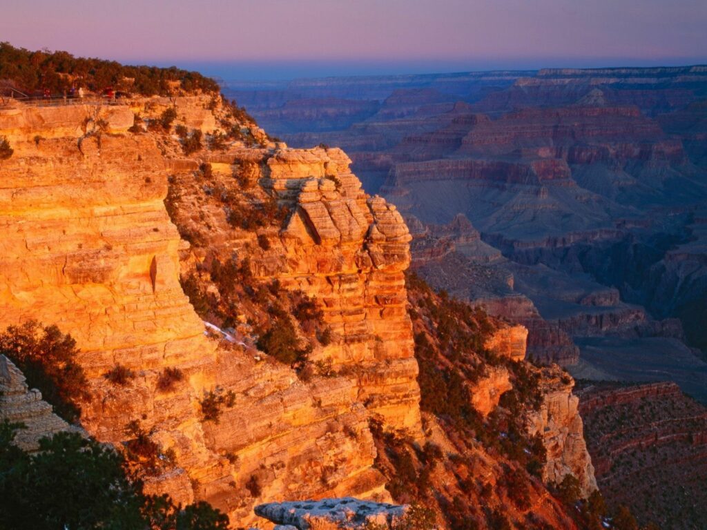 Grand Canyon cliffs in golden sunlight showcasing layered rock formations and vast canyon views Wallpaper