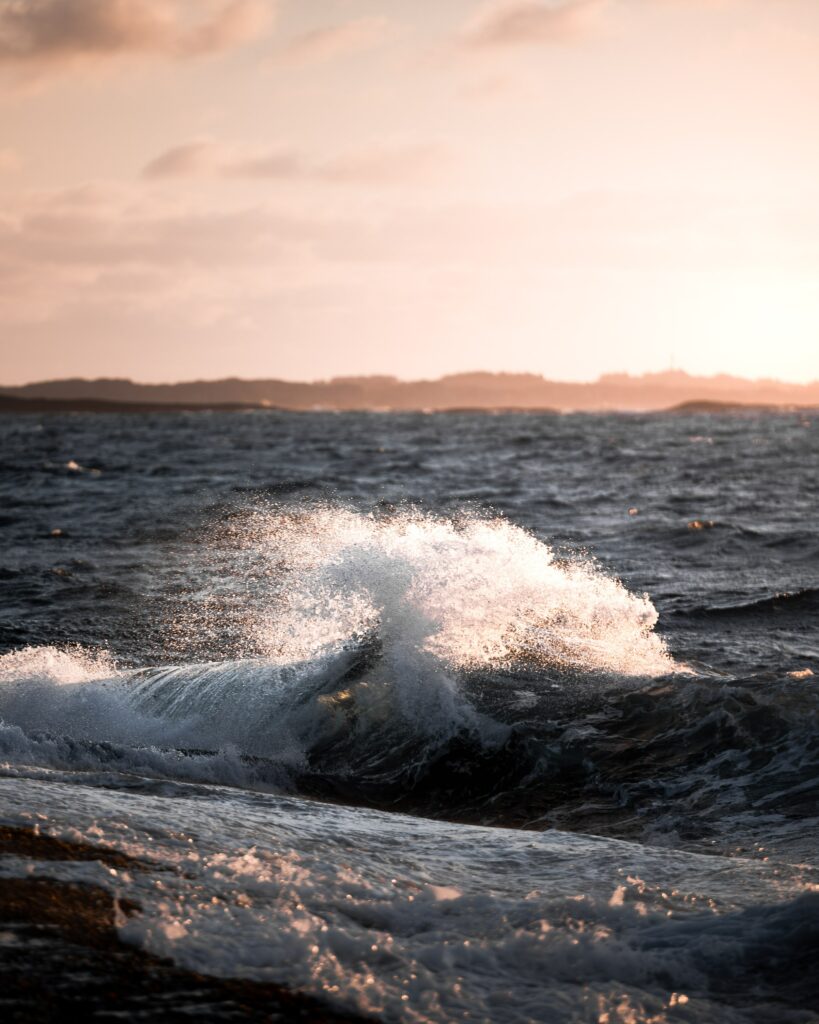 Powerful ocean wave crashing with golden sunlight highlighting deep blue water textures wallpaper