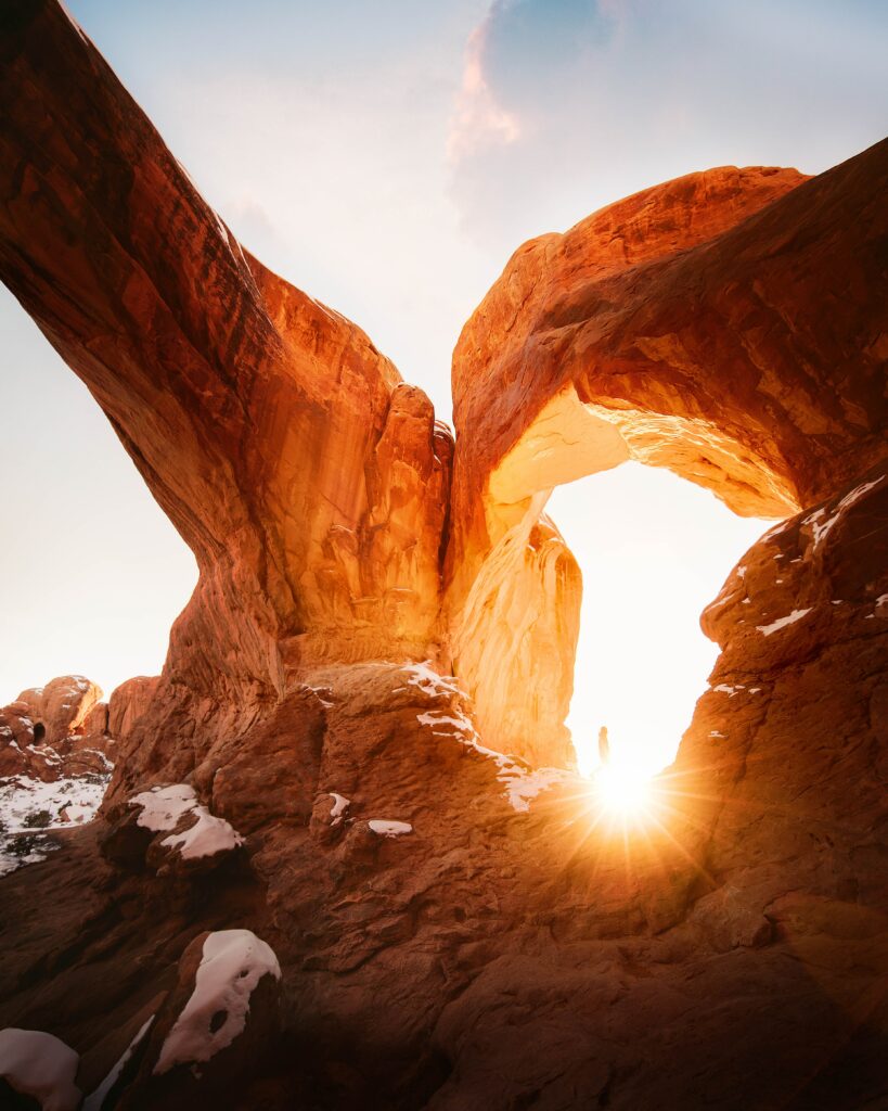 Sunlit rock formations with natural stone arch casting golden light and dramatic shadows wallpaper
