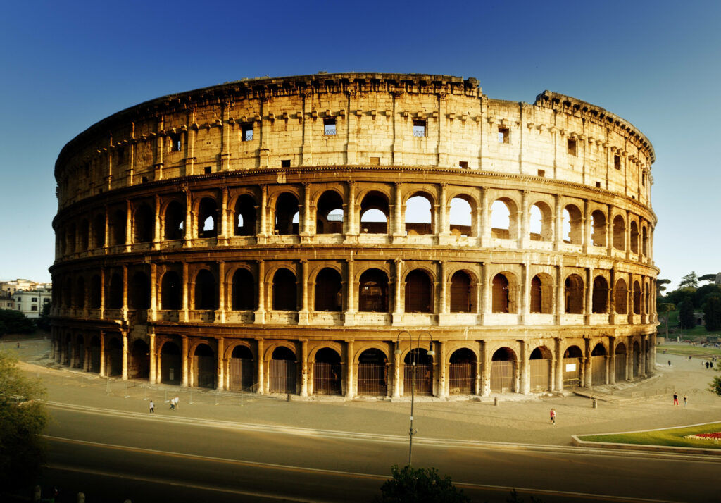 Colosseum in Rome bathed in golden sunlight under clear blue sky ancient amphitheater wallpaper