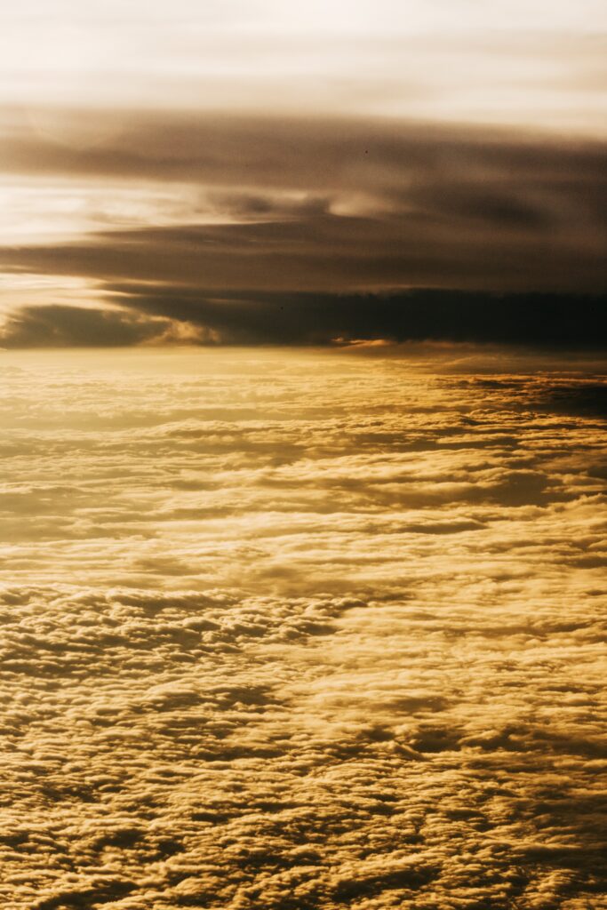 Aerial view of golden sunlight over endless clouds with warm tones and dramatic shadows Wallpaper