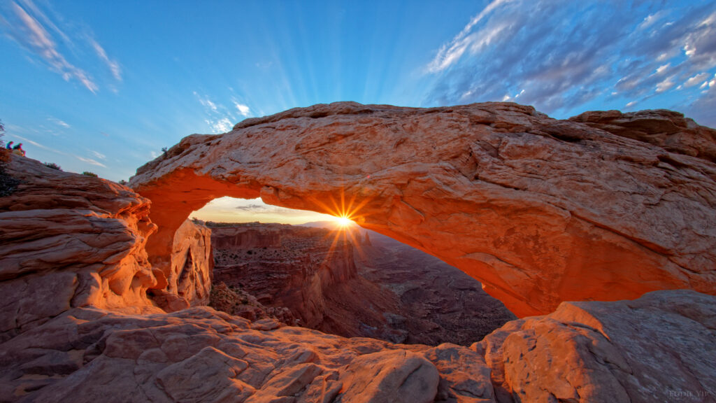 Natural stone arch at sunrise with golden light vibrant blue sky and dramatic rock textures wallpaper