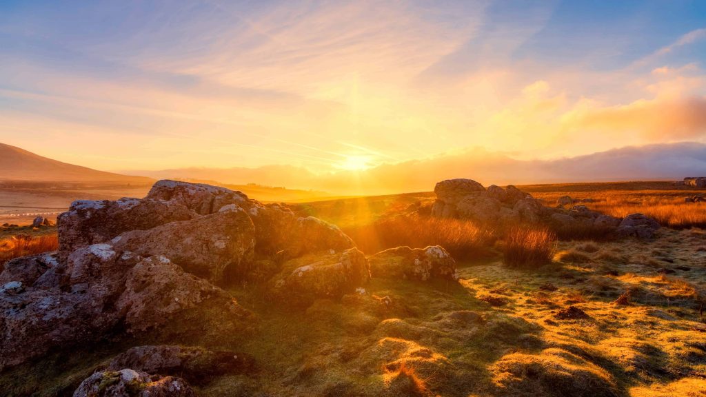 Golden sunrise over rugged moorland with mossy rocks peaceful nature desktop wallpaper
