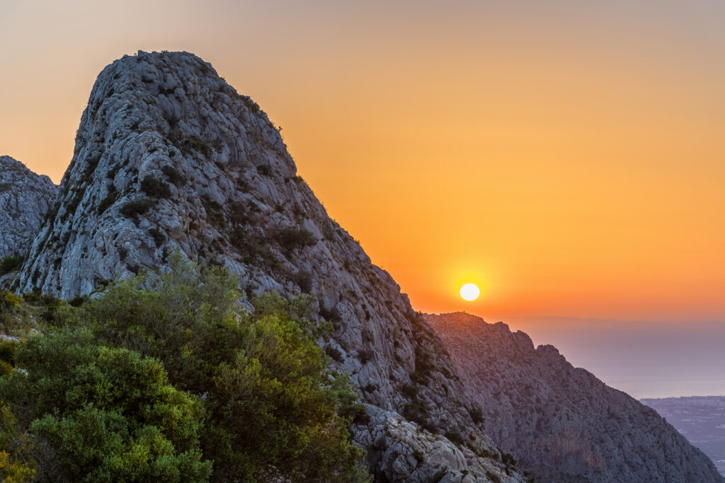 Golden sunrise over rugged mountain casting warm hues on tranquil natural landscape wallpaper