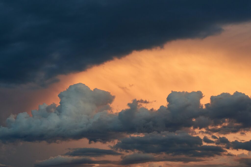 Dramatic sunset clouds with golden hues blending deep blue and orange evening sky wallpaper