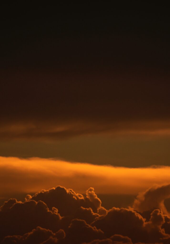 Sunset wallpaper with golden light and dramatic clouds in deep orange and dusky tones